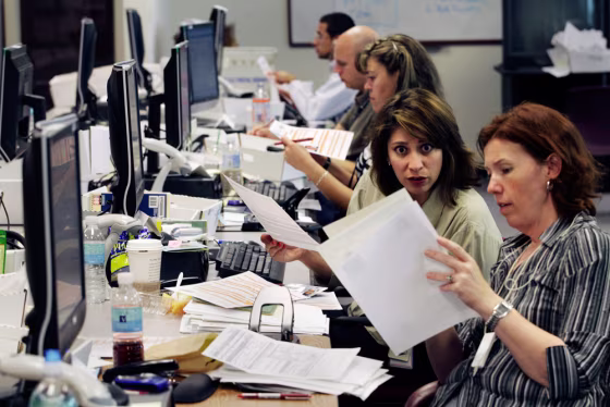 Katherine Estes, formerly assigned to Islamabad, Pakistan, right, looks at a passport application with Christina Bernal formerly from Juarez, Mexico, as they work to reduce the passport backlog earlier this summer.
