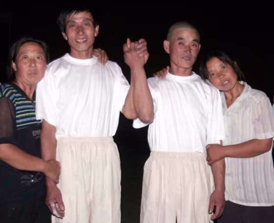 Meng Xianchen and Meng Xianyou, two brothers who tunnelled their way out of a coal mine collapse after being trapped for nearly six days, pose for photographers with their wives during an interview in Beijing