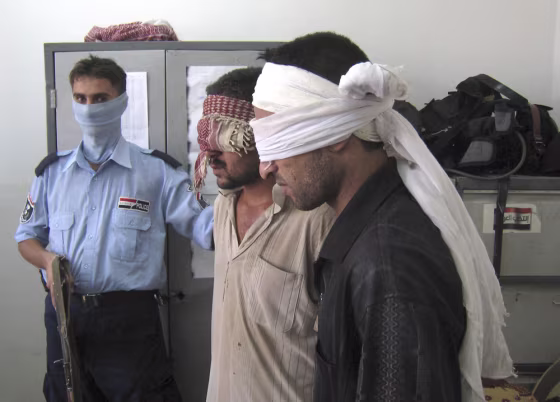 An Iraqi police officer guards two detainees&nbsp;who&nbsp;were arrested as&nbsp;they&nbsp;tried to launch a Katusha rocket at the &nbsp;Kirkuk airport, north of Baghdad, on Sunday.