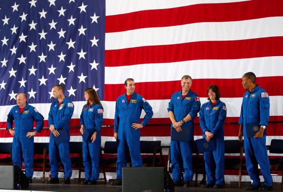 Space shuttle Endeavour astronauts stand in front of a large U.S. flag after their return to Houston, Wednesday, Aug. 22, 2007. The crew, from left: Commander Scott Kelly, Pilot Charles Hobaugh, Mission Specialists Tracy Caldwell, Richard Mastracchio, Dave Williams (from the Canadian Space Agency), Barbara R. Morgan and Alvin Drew.