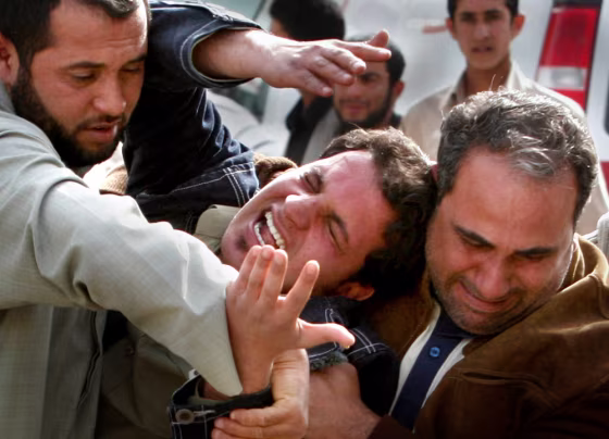 Men hold their cousin after his brother was killed in a suicide bomb attack in Baghdad