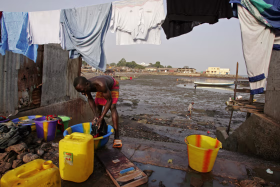 A man does his washing at a local fishing village at Conakry, Guinea. Entire neighborhoods in the capital haven't had electricity or running water for years.&nbsp; 