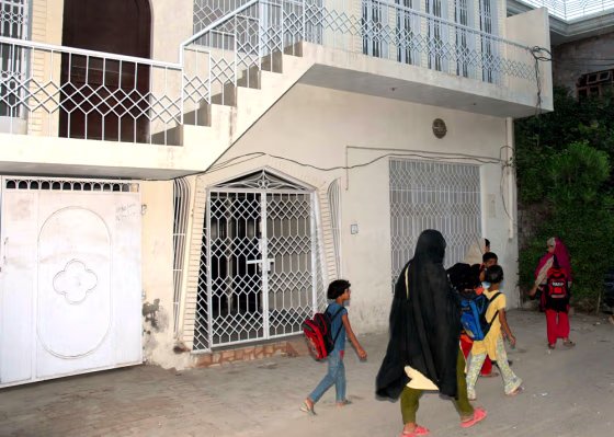 Pakistani students walk past the house believed to be that of Rashid Rauf, an alleged leader in the reported plot to blow up jetliners bound for the United States with liquid explosives.