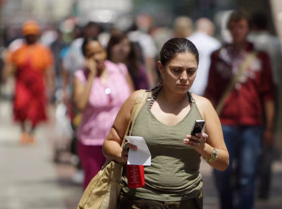 Image: A woman uses her cell phone to text message while walking.
