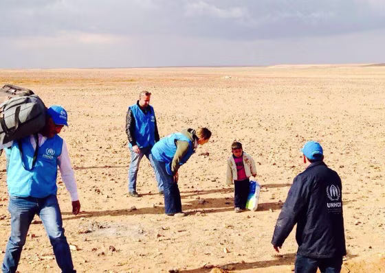 Marwan, a 4-year-old Syrian refugee who had been temporarily separated from his family, is assisted by UNHCR staff as he crosses the desert that straddles the Syrian border with Jordan.