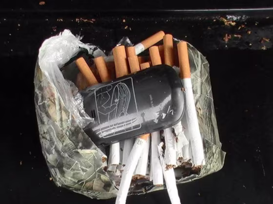 Image: A cellphone and cigarettes that were found inside a camouflage package near an undisclosed Florida state prison on Jan. 25, 2014.