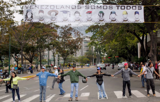 Image: Demonstrators join hands to block the highway at Altamira neighborhood in Caracas