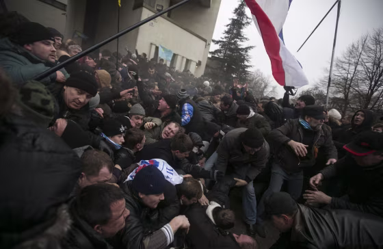 Image: Ukrainian men help pull one another out of a stampede during clashes at rallies held by ethnic Russians and Crimean Tatars in Simferopol
