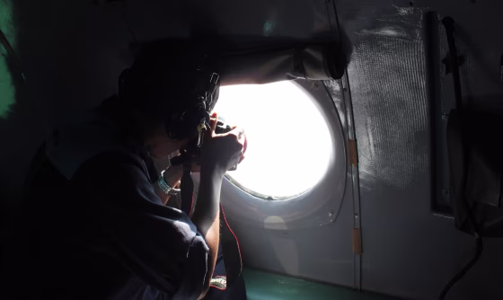 Image: A Vietnamese Air Force officer takes photos from a search and rescue aircraft in the search area for a missing Malaysia Airlines plane