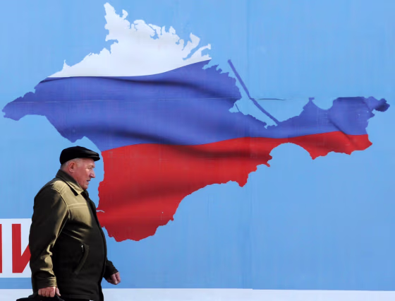 Image: A man walks past a poster in Sevastopol