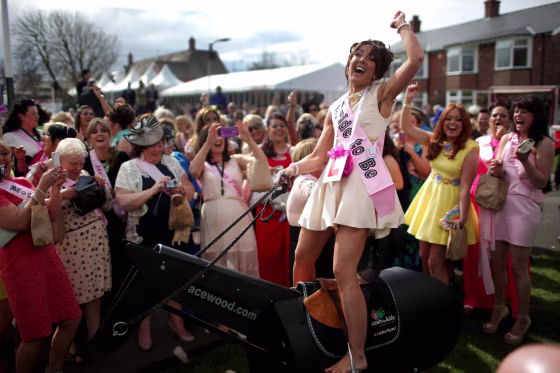 Bride-to-be Gemma Blease enjoys a ride on a horse racing simulator as she and her hen party enjoy the atmosphere of Ladies Day at the Aintree Grand National Festival on April 4, 2014 in Aintree, England. Friday is traditionally Ladies Day at the three-day meeting of the world famous horse race where fashion and dressing to impress is as important as the racing.