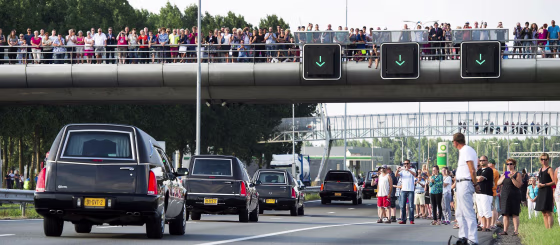 Image: People look as hearses carrying the remains of victims of flight MH17 are escorted on highway A27 near Nieuwegein by military police