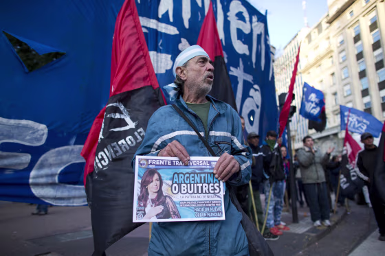 Image: An activist holds a newspaper with a headline that reads in Spanish \"Argentina or vultures,\"