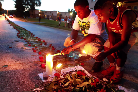 Image: Theo Murphy, left, of Florissant, Mo., and his brother Jordan Marshall, 11, light candles at a memorial on Canfield Drive in Ferguson, Mo.