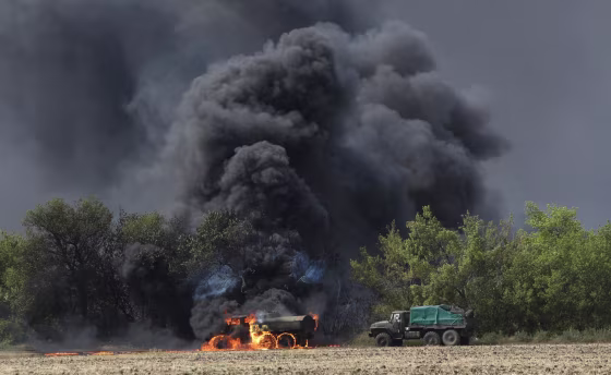 Image: An unmarked military vehicle burns on a country road in the village of Berezove, eastern Ukraine