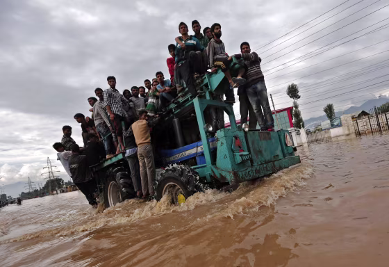 Image: A tractor evacuating Kashmiri flood victims to higher grounds travels through a flooded street in Srinagar