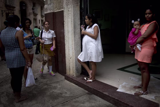 In this Oct. 22, 2014 photo, a pregnant woman a pregnant woman drinks a soft drink at the entrance of a special maternity unit for high-risk pregnancies in Havana, Cuba. The island nation has long prided itself on care of pregnant women and newborns, and officials often boast of an infant mortality rate lower than that of the United States. (AP Photo/Ramon Espinosa)