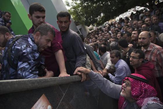Image: Palestinian Hamas police officers stand guard outside a post office where hundreds of employees of the former Hamas government line up to receive wages