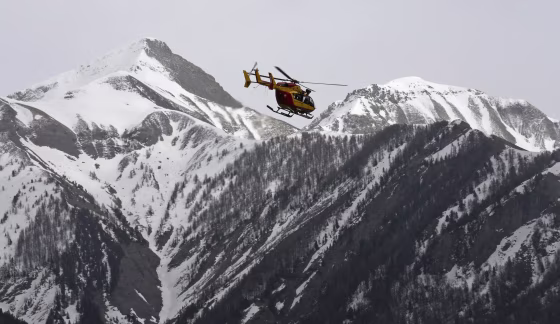 Image: A rescue helicopter from the French Securite Civile flies over the French Alps during a rescue operation following the crash of an Airbus A320