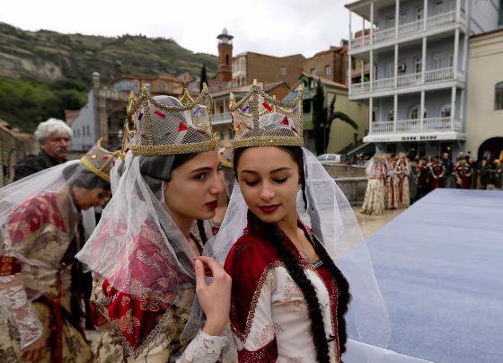 Image: Young Georgian musicians wearing traditional outfits chat during 'Tbilisoba' celebrations