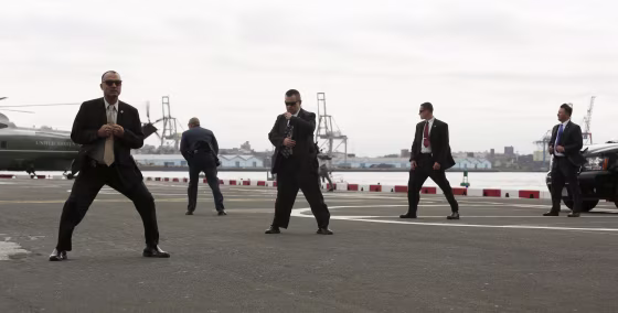 Image: U.S. Secret Service agents brace themselves against the prop wash from Marine One as U.S. President Barack Obama arrives at the Wall St. Heliport in New York