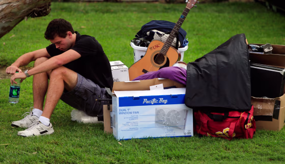 Image: A freshman waits with his belongings for his family to arrive to help him move into his dorm