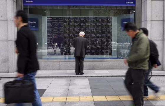 Man looks at a stock quotation board outside a brokerage in Tokyo