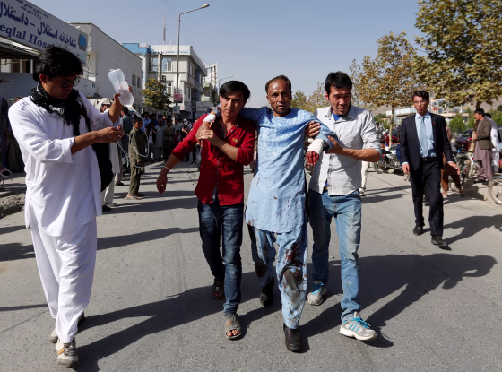 Image: Men help an injured man outside a hospital after a suicide attack in Kabul