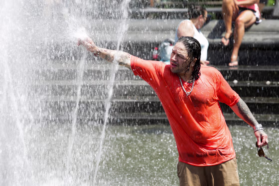 Image: A man cools off himself on a fountain during a heat wave called "Heat Dome" in the Manhattan borough of New York, U.S.