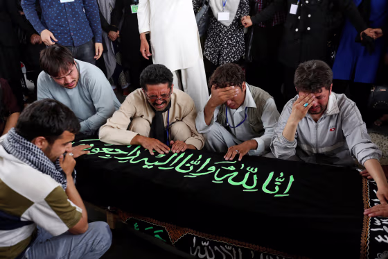 Image: Men mourn over the coffin of a victim a day after a suicide attack in Kabul, Afghanistan