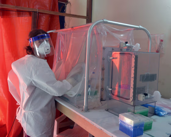 Emmie de Wit of the National Institute of Allergy and Infectious Diseases at the diagnostic laboratory in Monrovia, Liberia, using a sealed glovebox to deactivate virus in patient blood samples before testing for Ebola.