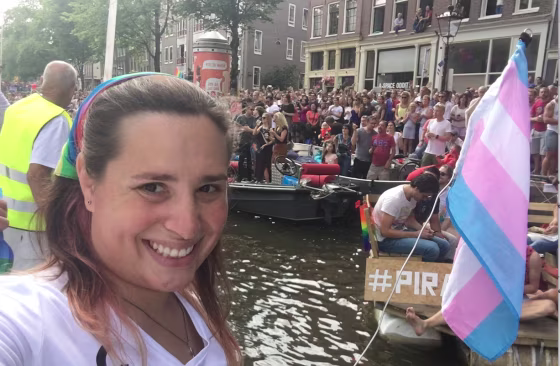 Trans activist Hannah Simpson, waving the transgender pride flag, takes a selfie from aboard the World Religion Boat during Amsterdam's EuroPride 2016 Canal Parade.