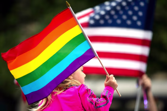 A Pride participant holds a rainbow flag.