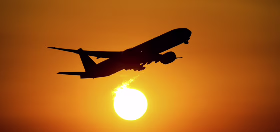 An airplane starts into the sunset from the airport.