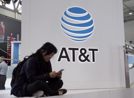 A woman looks at her mobile next to AT&T logo during the Mobile World Congress in Barcelona