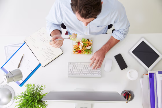 Image: A man eats lunch at his desk