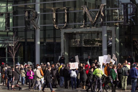 Image: Protesters hold signs outside of the Trump International Hotel and Tower during its grand opening in Vancouver