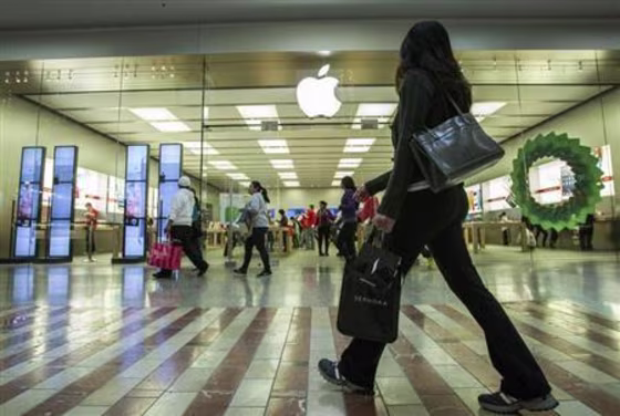People walk past the Apple Store while shopping at the Los Cerreitos Center mall on Black Friday in Cerritos