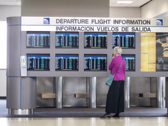 Image: Bilingual Departure Flight Information Board and Passenger, Newark Liberty International Airport, Newark, New Jersey, USA. Image shot 2012.