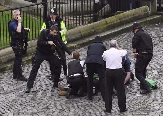 A police officer points a gun at a man on the ground outside the Palace of Westminster on Wednesday.