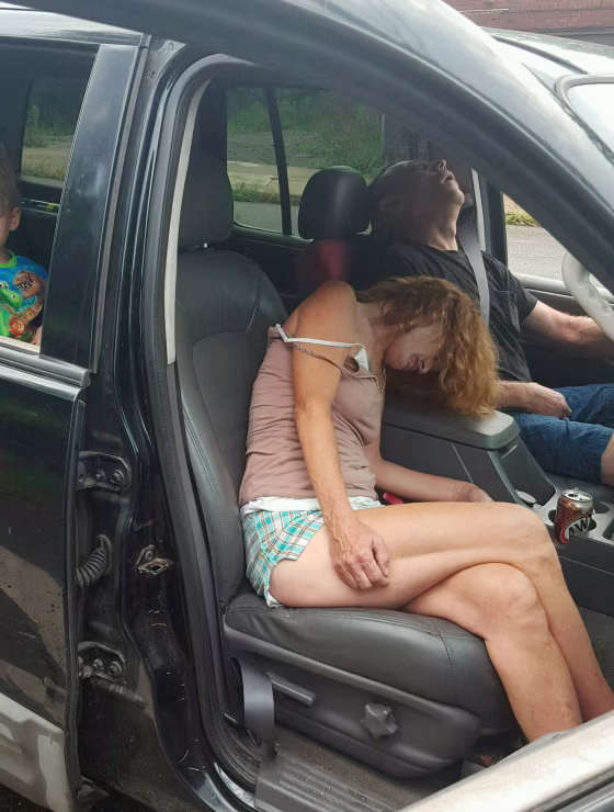 Image: East Liverpool Police Department photo showing two adults passed out in a car with a little boy in the backseat