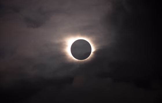 Image: A total solar eclipse is visible through the clouds as seen from Vagar on the Faeroe Islands, Friday, March 20, 2015.