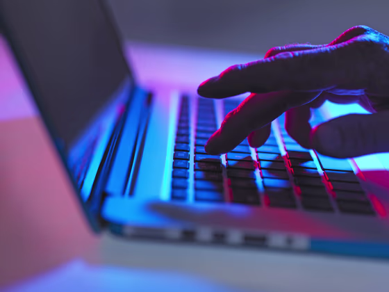 Silhouette of male hand typing on laptop keyboard at night
