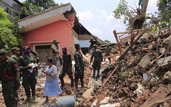Image: Sri Lankan army rescuers remove debris from a buried house
