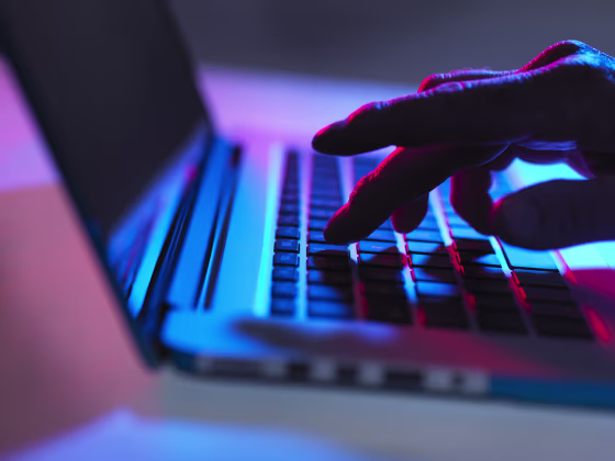 Image: Silhouette of male hand typing on laptop keyboard at night