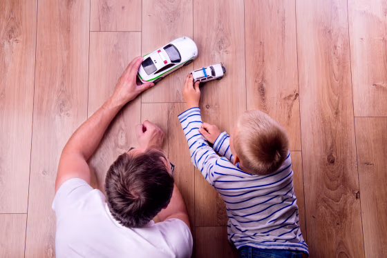 Image: A father with his son playing with cars.