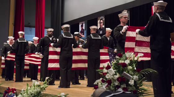 Image: Sailors fold seven U.S. flags during a memorial ceremony