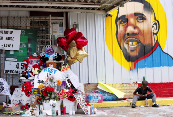 Image: FILE PHOTO: A boy sits next to a makeshift memorial outside the Triple S Food Mart where Alton Sterling was fatally shot by police in Baton Rouge