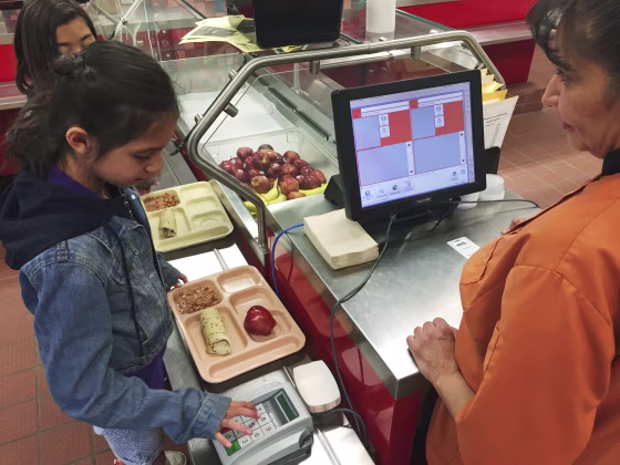 Image: third grader Elliana Vigil punches in her student identification meal to pay for a meal at Gonzales Community School