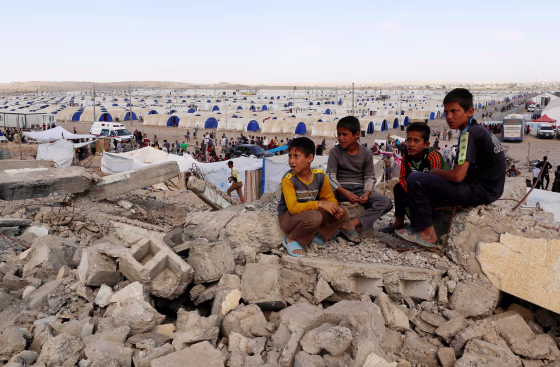 Image: Displaced Iraqi children who fled their homes sit on debris outside Hammam al-Alil camp south of Mosul